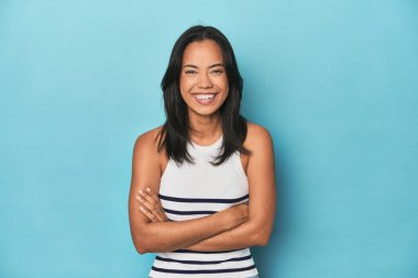 Mavi stüdyodaki Filipinli genç kadın gülüyor ve eğleniyor..