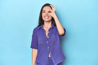 Mavi arka plandaki genç beyaz kadın heyecanlandı. Gözünü dört aç..