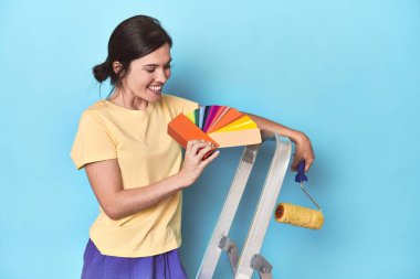 Renk paletli kadın merdivene duvar boyuyor.