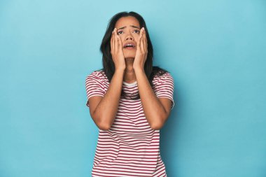 Filipinli genç kadın mavi stüdyoda sızlanıyor ve ağlıyor..