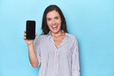 Mavi arkaplanda telefon ekranı gösteren kadın