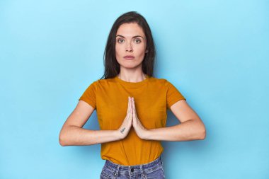 Mavi arka planda dua eden, kendini adamış dindar, ilahi ilhamı arayan beyaz bir kadın..