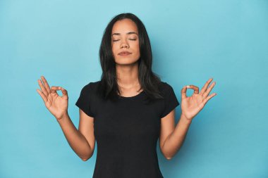 Mavi stüdyodaki Filipinli genç kadın yorucu bir günün ardından dinleniyor, yoga yapıyor..