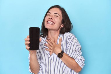 Mavi ekranda telefon ekranı gösteren umut dolu kadın.