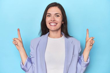 Mavi arka plandaki mavi ceketli kadın iki ön parmağı da boş bir alan gösteriyor..