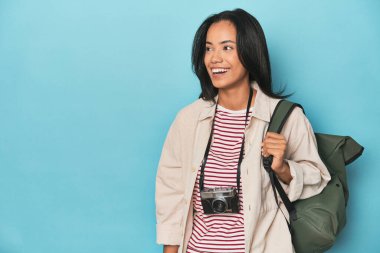 Filipinli kamera ve seyahat çantasıyla mavi stüdyo arka planında