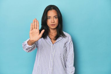 Mavi stüdyodaki Filipinli genç kadın elini uzatmış, dur işareti gösteriyor ve seni engelliyor..