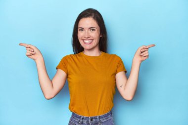 Mavi arka planda genç beyaz bir kadın farklı kopya alanlarını gösteriyor, birini seçiyor, parmaklarıyla gösteriyor..