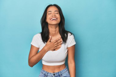 Mavi stüdyodaki Filipinli genç kadın elini göğsüne koyarak kahkahalar atıyor..