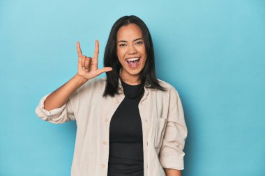 Mavi stüdyodaki Filipinli genç kadın devrim konsepti olarak boynuzlarını gösteriyor..