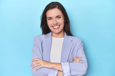 Mavi ceketli, kendine güveni tam, kararlılıkla kollarını kavuşturan bir kadın..