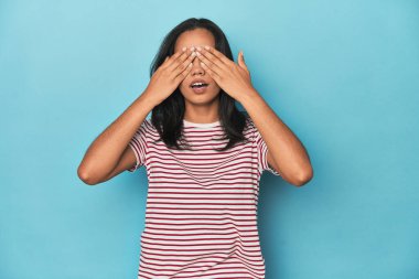 Mavi stüdyodaki Filipinli genç kadın elleriyle gözlerini kapatmaktan korkuyor..