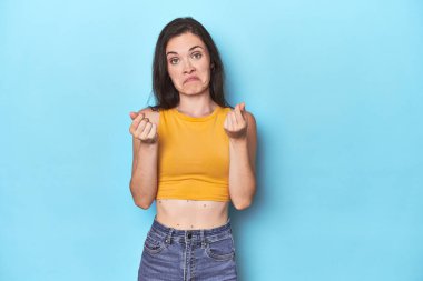 Mavi arka plandaki genç beyaz kadın parasız olduğunu gösteriyor..