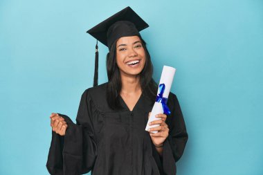 Mavi stüdyoda diploma ve şapkayla Filipinli mezuniyeti kutluyoruz.