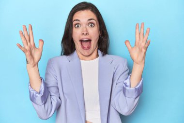 Mavi ceketli kadın zaferi ya da başarıyı kutluyor. Şaşırdı ve şok oldu..