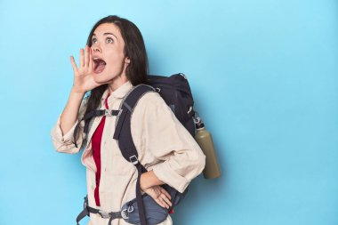 Sırt çantalı maceraperest bir kadın bağırıyor ve ağzı açık bir şekilde avucunu tutuyor..