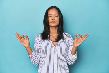 Mavi stüdyodaki Filipinli genç kadın yorucu bir günün ardından dinleniyor, yoga yapıyor..