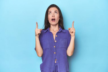 Mavi arka planda ağzı açık, üst tarafı gösteren beyaz bir kadın..