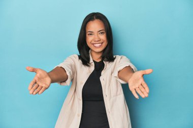 Mavi stüdyodaki Filipinli genç kadın hoş bir yüz ifadesi sergiliyor.