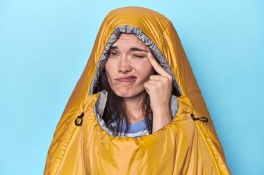 Mavi arka planda uyku tulumundaki kadın işaret parmağıyla bir hayal kırıklığı gösteriyor..