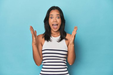 Mavi stüdyodaki Filipinli genç kadın zaferi ya da başarıyı kutluyor. Şaşırdı ve şok oldu..