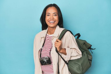 Filipinli kamera ve seyahat çantasıyla mavi stüdyo arka planında