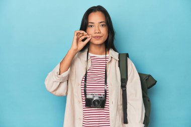 Kameralı ve mavi çantalı Filipinli kadın parmakları dudaklarında bir sır saklıyor..