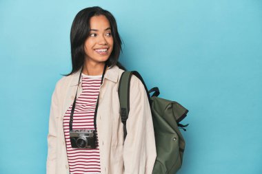 Kameralı ve mavi çantalı Filipinli kadın gülümseyen, neşeli ve keyifli görünüyor..