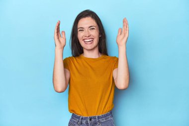 Mavi arka plandaki genç beyaz kadın çok gülerdi. Mutluluk kavramı.