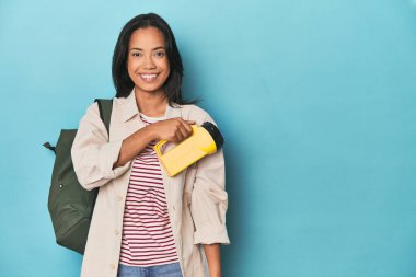 Filipinli, mavi stüdyoda fener ve sırt çantasıyla gezintileri destekliyor.