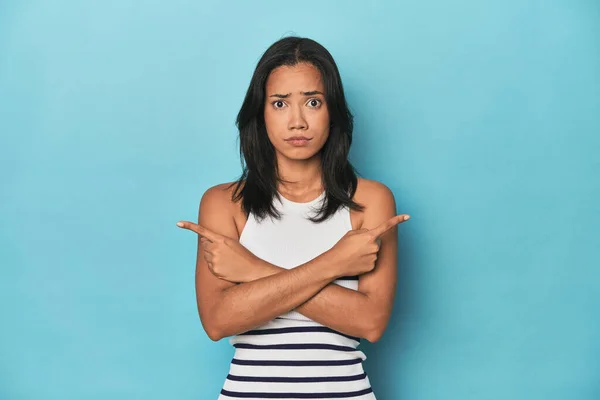 Filipina Young Woman Blue Studio Points Sideways Trying Choose Two — Stock Photo, Image