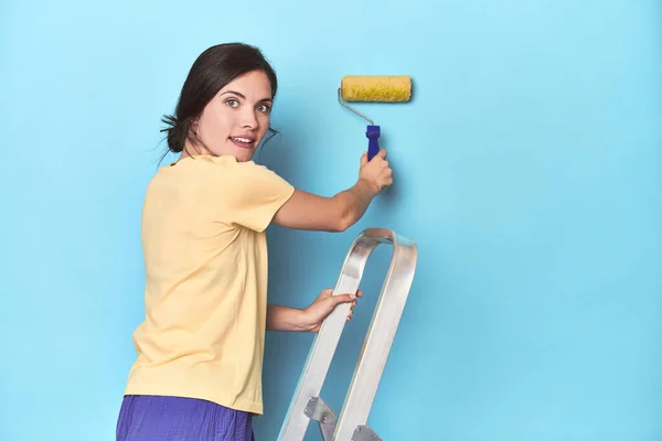 Mulher Pintando Uma Parede Azul Uma Escada — Fotografia de Stock