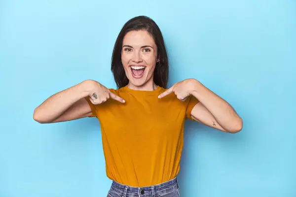 Young Caucasian Woman Blue Backdrop Surprised Pointing Finger Smiling Broadly — Stock Photo, Image