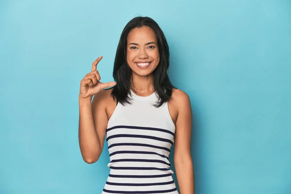 Filipina Young Woman Blue Studio Holding Something Little Forefingers Smiling — Stock Photo, Image