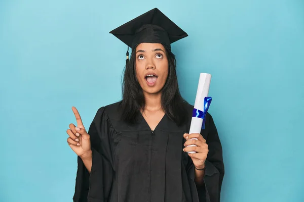 Filipina Graduate Diploma Blue Studio Pointing Upside Opened Mouth — Stock Photo, Image