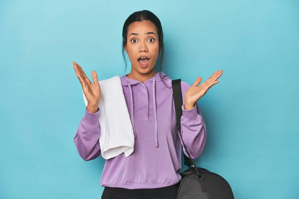 Filipina with gym gear on blue studio surprised and shocked.