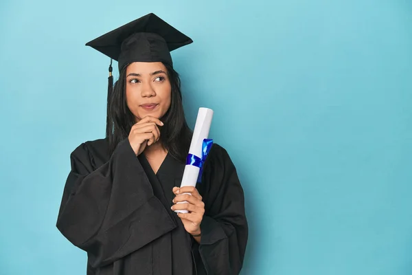 Filipina Graduate Diploma Blue Studio Looking Sideways Doubtful Skeptical Expression — Stock Photo, Image