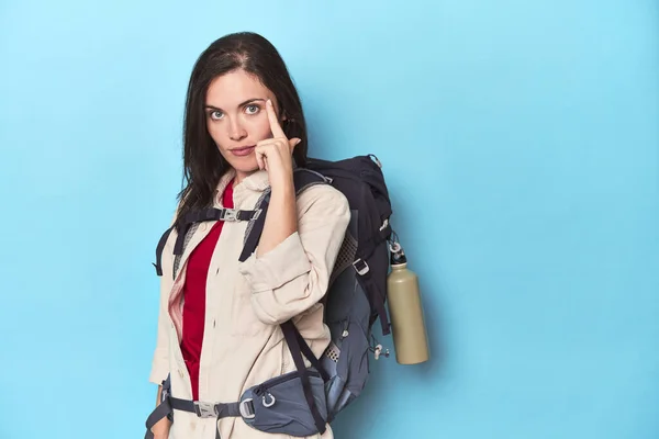 Adventurous Woman Backpack Blue Pointing Temple Finger Thinking Focused Task — Stock Photo, Image