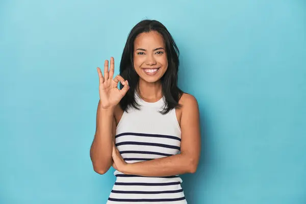 Filipina Young Woman Blue Studio Winks Eye Holds Okay Gesture — Stock Photo, Image