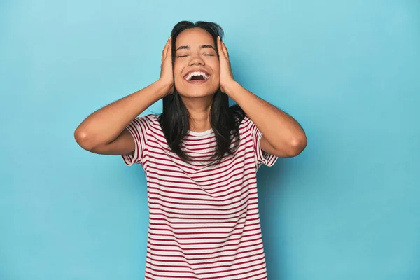 Filipina Young Woman Blue Studio Laughs Joyfully Keeping Hands Head — Stock Photo, Image