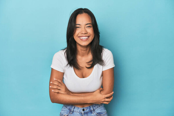 Filipina young woman on blue studio laughing and having fun.