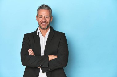 Mavi stüdyo arka planında resmi giyinmiş bir iş adamı.