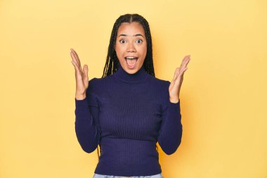 Sarı stüdyo stüdyosundaki genç Endonezyalı kadın zaferi ya da başarıyı kutluyor, şaşırıyor ve şok oluyor..