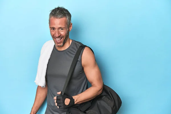 Athlete with gym backpack on blue studio backdrop