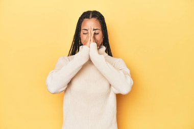 Sarı stüdyo stüdyosundaki genç Endonezyalı kadın el ele tutuşup ağza yakın dua ediyor..