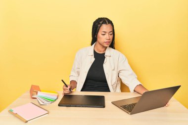 Sarı stüdyoda grafik tablet, bilgisayar ve renk paleti olan Endonezyalı tasarımcı