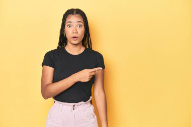 Sarı stüdyodaki genç Endonezyalı kadın yan tarafı işaret ediyor.