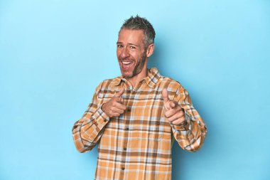 Mavi zemin üzerinde orta yaşlı beyaz adam parmaklarıyla ön tarafı işaret ediyor..