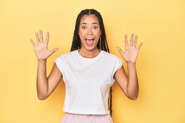 Sarı stüdyodaki genç Endonezyalı kadın hoş bir sürpriz alıyor, heyecanlı ve el kaldırıyor..