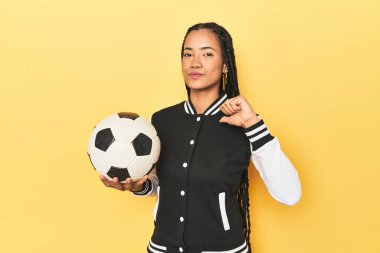 Futbol topu sarılı Endonezyalı kız gururlu ve kendinden emin hissediyor, örnek olarak..